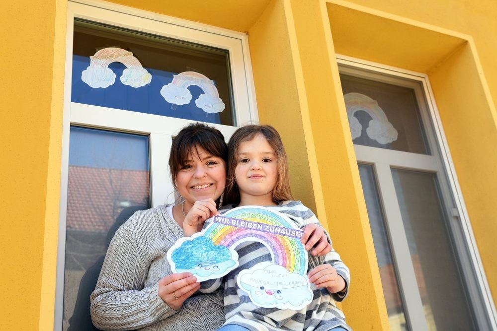 Lisa Schöppe vom Verein „Radegast beleben“ und ihr sechsjähriges Töchterchen Charlotte bestückten ihre Fenster mit selbst gemalten Regenbögen. Sie machen mit bei der Regenbogen-Aktion. Inzwischen schmücken etliche farbenfrohe Regenbögen Haustüren und Fenster - nicht nur in Radegast.