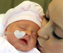 Auf der Kinderstation der Klinik für Geburtshilfe vom Krankenhaus St. Elisabeth und St. Barbara in Halle (Saale) kuschelt Katja Frühauf mit ihrer sieben Tage alten Tochter Karolina. (Foto: dpa)
