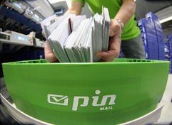 Ein Mitarbeiter steckt Briefe in eine grüne Briefkiste im Sortierzentrum der Pin Mail AG in Berlin. (Foto: ddp)