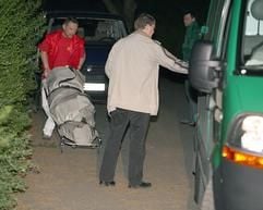 Männer transportieren die verkohlte Leiche einer etwa 20 Jahre alten Frau in einer Grünanlage in Berlin-Neukölln ab. (Foto: dpa)