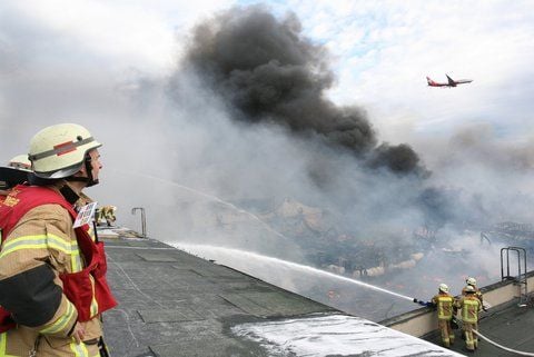 Ein Flugzeug fliegt am Donnerstag in Berlin im Landeanflug zum Flughafen Tegel über dichte Rauchwolken. In einer Lagerhalle war am frühen Morgen ein Großbrand ausgebrochen. (FOTO: DPA)