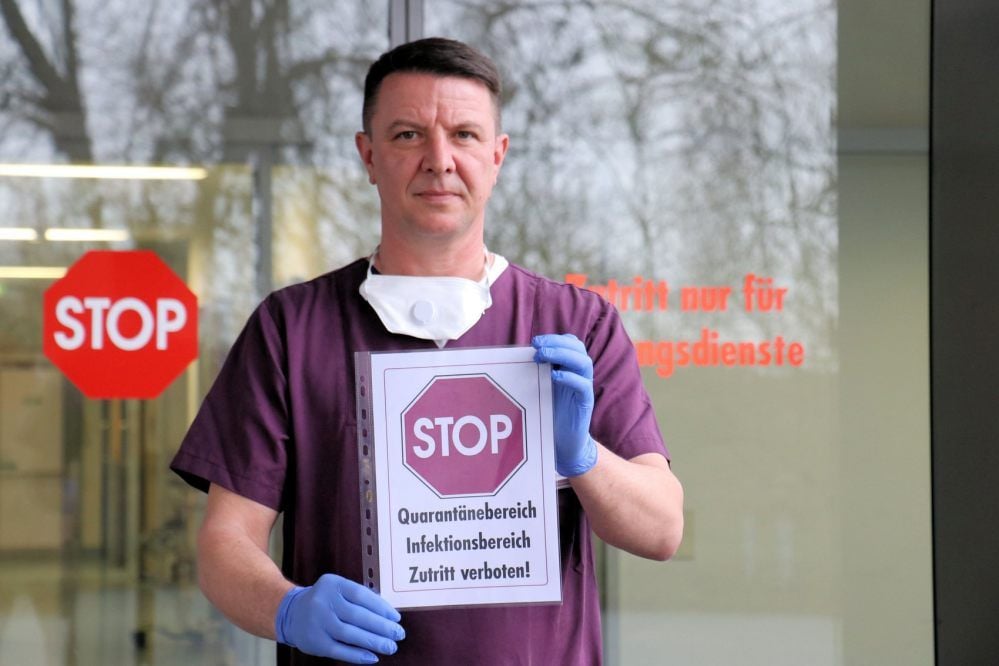 Christian Hirsch, Pflegerischer Leiter der Notaufnahme am Quedlinburger Harzklinikum, mit einem Hinweisschild, das im Krankenhaus angebracht wird, wenn wegen der Coronavirus-Ausbreitung Quarantänebereiche im Krankenhaus ausgewiesen werden müssen.