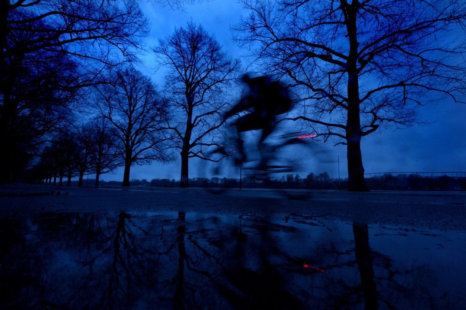 Ein Radfahrer fährt im Nieselregen in der Morgendämmerung.