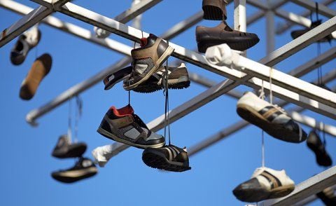 Mehrere Paar Schuhe hängen an einem ehemaligen Werbeträger in Leipzig. (FOTO: DPA)