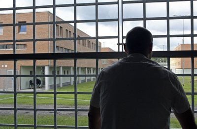 Ein Mann schaut durch ein vergittertes Fenster auf die Anlagen der 2007 übergebenen Jugendhaftanstalt Regis-Breitingen (FOTO: DPA)