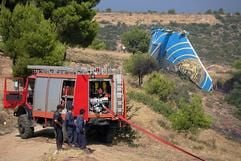 Feuerwehrleute stehen nahe der griechischen Hauptstadt Athen unweit einer abgerissenen Tragfläche der abgestürzten Boeing 737-300 an einem Fahrzeug. (Foto: dpa)