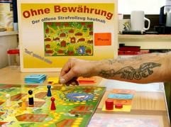 Gefangene der JVA-Moers-Kapellen spielen mit einer Sozialarbeiterin und Spiel-Ideegeberin unter der Aufsicht von zwei Vollzugsbeamten in einem Haftraum das von ihnen erarbeitete Brettspiel «Ohne Bewährung». (Foto: dpa)