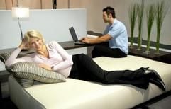Denise (l) und Justin testen auf der internationale Möbelmesse «imm cologne» in Köln ein neuartiges Sitzmöbel von Rolf Benz, auf dem man sitzen, relaxen, schlafen und arbeiten kann (Foto: dpa)