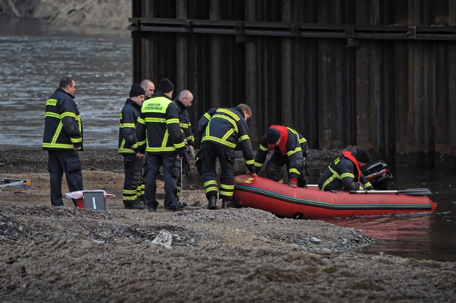 Feuerwehrleute besteigen am Muldewehr in Dessau ein Spezialboot.