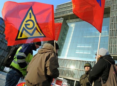 Mitarbeiter stehen mit Fahnen der Gewerkschaft IG Metall vor der ThyssenKrupp Zentrale in Essen. (FOTO: ARCHIV/DPA)