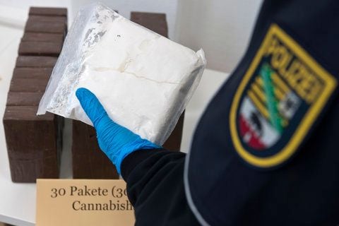 Der Pressesprecher der Polizeidirektion Nord, Bernhard Wessner, präsentiert in Magdeburg eine sichergestellte Tüte mit Amphetamin, während im Hintergrund 30 sichergestellte Pakete Cannabisharz liegen. (FOTO: DAPD)