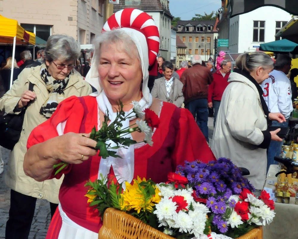 Die Marktfrau Regine ist mit guter Laune unterwegs. An die Besucher verschenkt sie bunte Blumen.