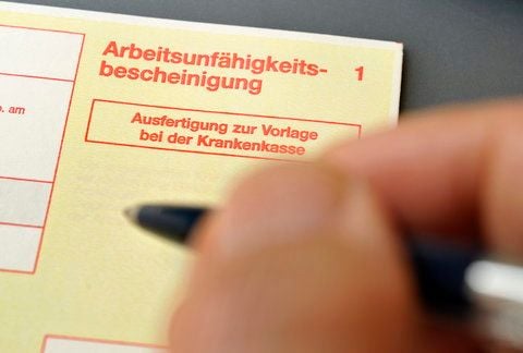 Ein Arzt füllt eine Arbeitsunfähigkeitsbescheinigung aus. (FOTO: DDP)