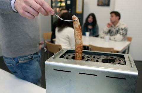 Der 25-jährige Ingenieur Felix Rennies nimmt in seiner Büroküche in Bremen eine gegrillte Bratwurst aus einem von ihm mit entwickelten «Wurst-Toaster». (FOTO: DAPD)