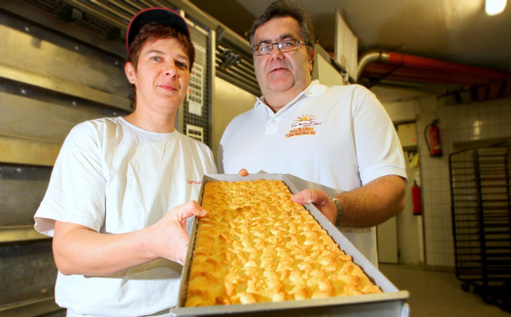 Der Bäckermeister Michael Tschirch mit seiner Mitarbeiterin Ina Junge und einem Blech Streuselkuchen in der Backstube der Bäckerei Tschirch in Nieder Neundorf bei Görlitz (Sachsen).