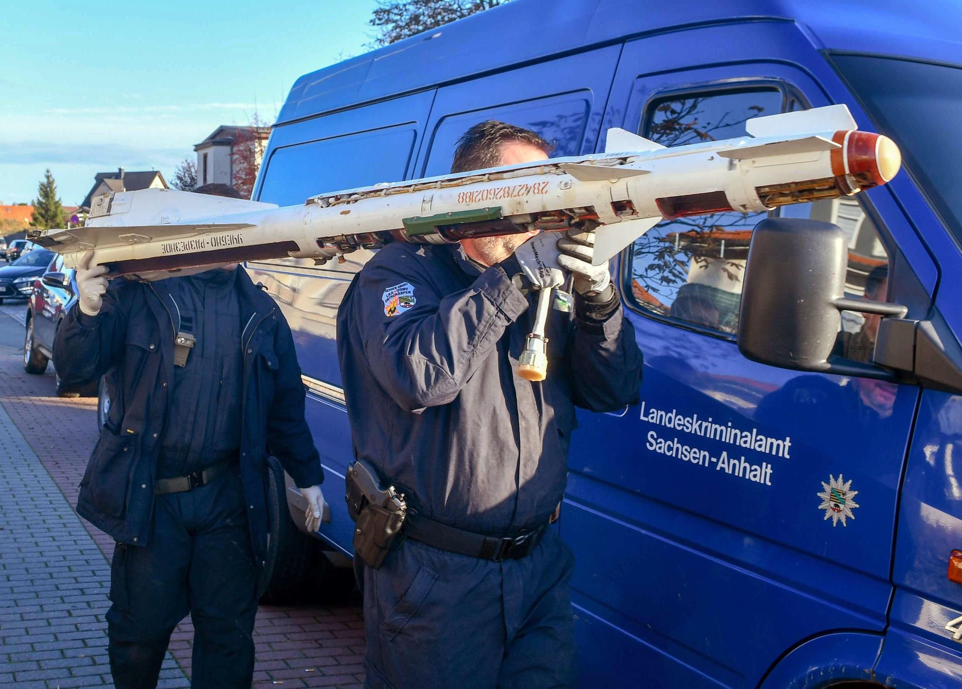 Experten des Kampfmittelbeseitigungsdienstes tragen eine sowjetische Luftrakete, die während der Wohnungsdurchsuchung sichergestellt wurde. Die Waffen stammen überwiegend aus dem Ersten und Zweiten Weltkrieg.