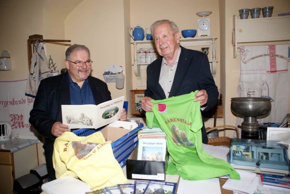 Artur Wellnitz (links) ist der neue Vorsitzende des Heimatvereines Droyßig. Der langjährige Chef Günter Koschig sucht mit ihm gemeinsam Dinge heraus wie die T-Shirts vom Bärenverein, die zum Schlossfest am Wochenende verkauft werden sollen.