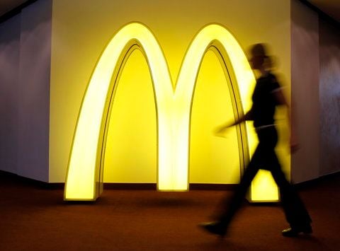 Eine Mitarbeiterin von McDonalds geht in München auf der Jahrespressekonferenz des Unternehmens vor einem leuchtenden Buchstaben «M» vorbei. (FOTO: DAPD)