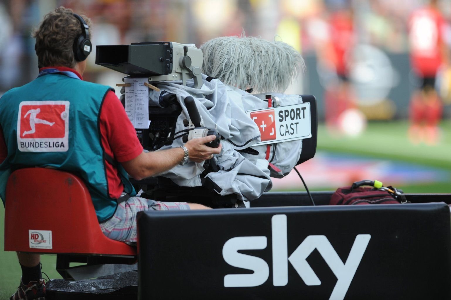 Ein Kameramann sitzt am 25.08.2012 vor einem Logo des Fernsehsenders «Sky» im Bundesliga-Spiel SC Freiburg gegen 1. FSV Mainz 05.