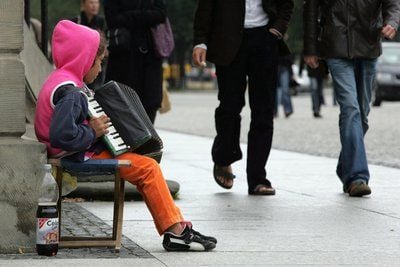 Ein junges Mädchen versucht in Berlin etwas Kleingeld mit Musizieren zu verdienen. (Foto: dpa)