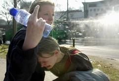 Eine Demonstrantin hilft am Montag (24.03.2003) während einer Protestaktion gegen den Krieg im Irak in der Hamburger Innenstadt in der Hamburger Innenstadt ihrer verletzten Freundin, während im Hintergrund mit Wasserwerfern versucht wird, die Demonstration zu beenden. Während einer Schülerdemonstration kam es zu Ausschreitungen. (Foto: dpa)