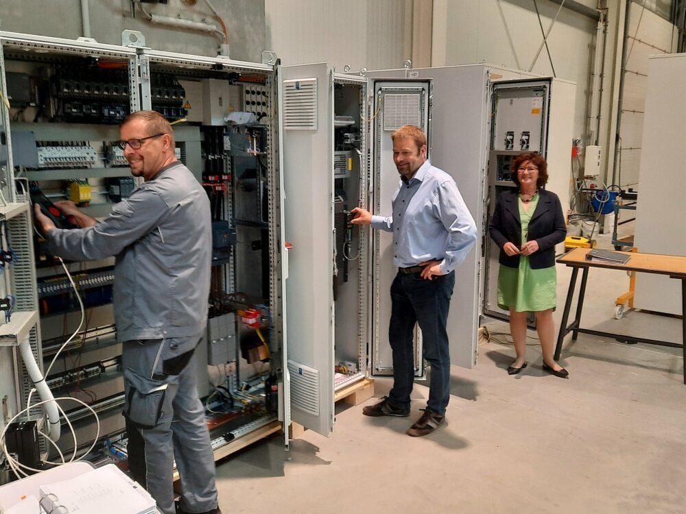 Werkstattmeister Peter Müller und Geschäftsführer Martin Schulze zeigen Petra Bratzke, Chefin der Arbeitsagentur, die Schaltschränke.