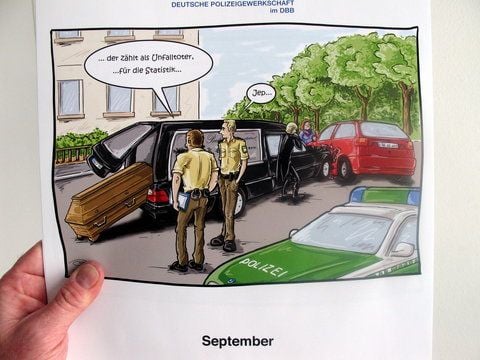 Die September-Karikatur des Kalenders zeigt eine Szene nach dem Unfall eines Leichenwagens. (FOTO: DPA)