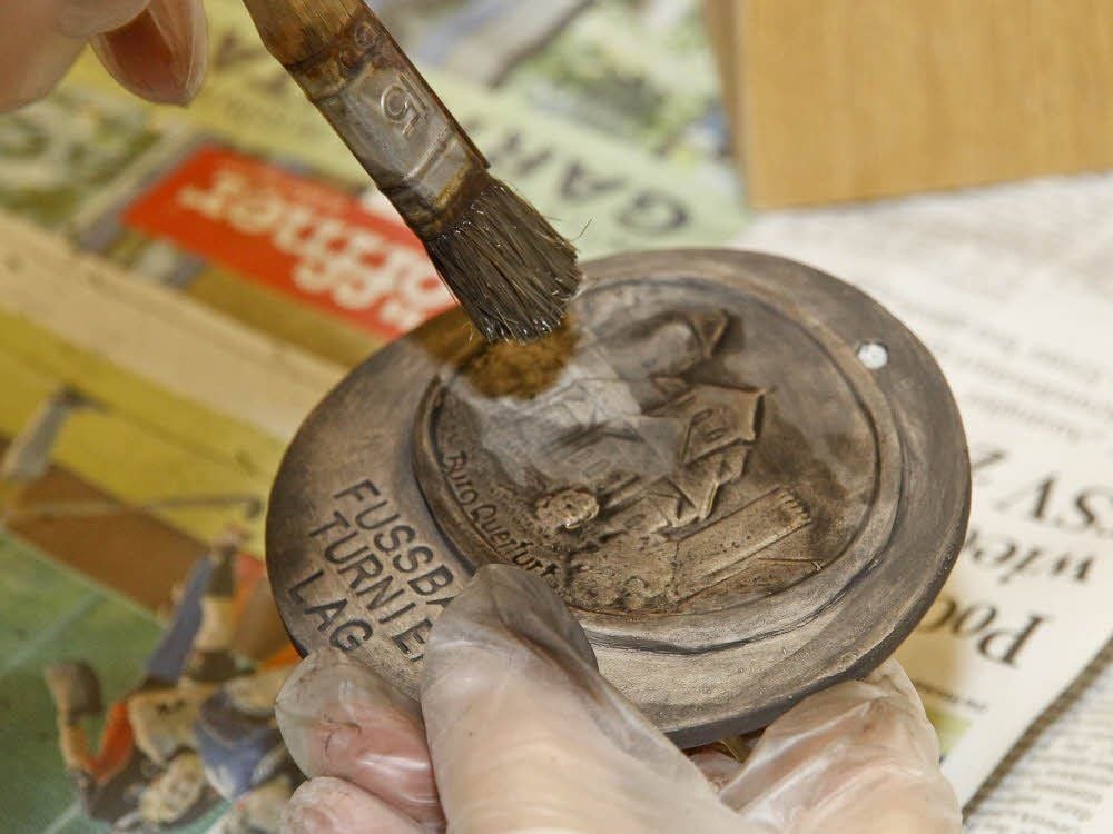 In Kleinarbeit werden die Medaillen bepinselt.