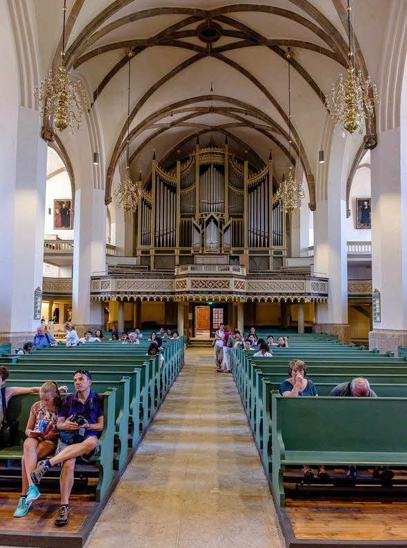 Im Zuge der Generalsanierung hat der Innenraum der Stadtkirche eine völlig neue Farbgestaltung bekommen. Hell ist er geworden, das sanfte Grün der Bänke korrespondiert mit dem kräftig leuchtenden Rot der Gewänder auf den Cranach-Gemälden. Prächtig ist die Sauer-Orgel, die über gut 4 200 Pfeifen verfügt.