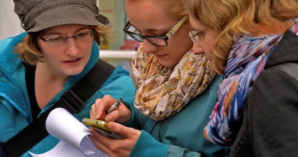 Geocaching-Tour durch Aschersleben: Sophie, Franziska und Marie (v.l.n.r.) suchen die Koordinaten auf ihrem Smartphone.