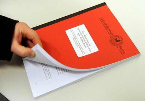 Ein Mann blättert in einer wissenschaftlichen Untersuchung der Freien Universität Berlin zu früheren Stasi-Kontakten von Polizisten. (FOTO: DPA)
