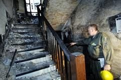 Ein Beamter des Brand-Kommissariats zeigt am Dienstag (9. August 2005) in Berlin-Moabit im Treppenhaus des ausgebrannten Wohnhauses auf die Stelle, wo der Brand ausbrach. (Foto: dpa)