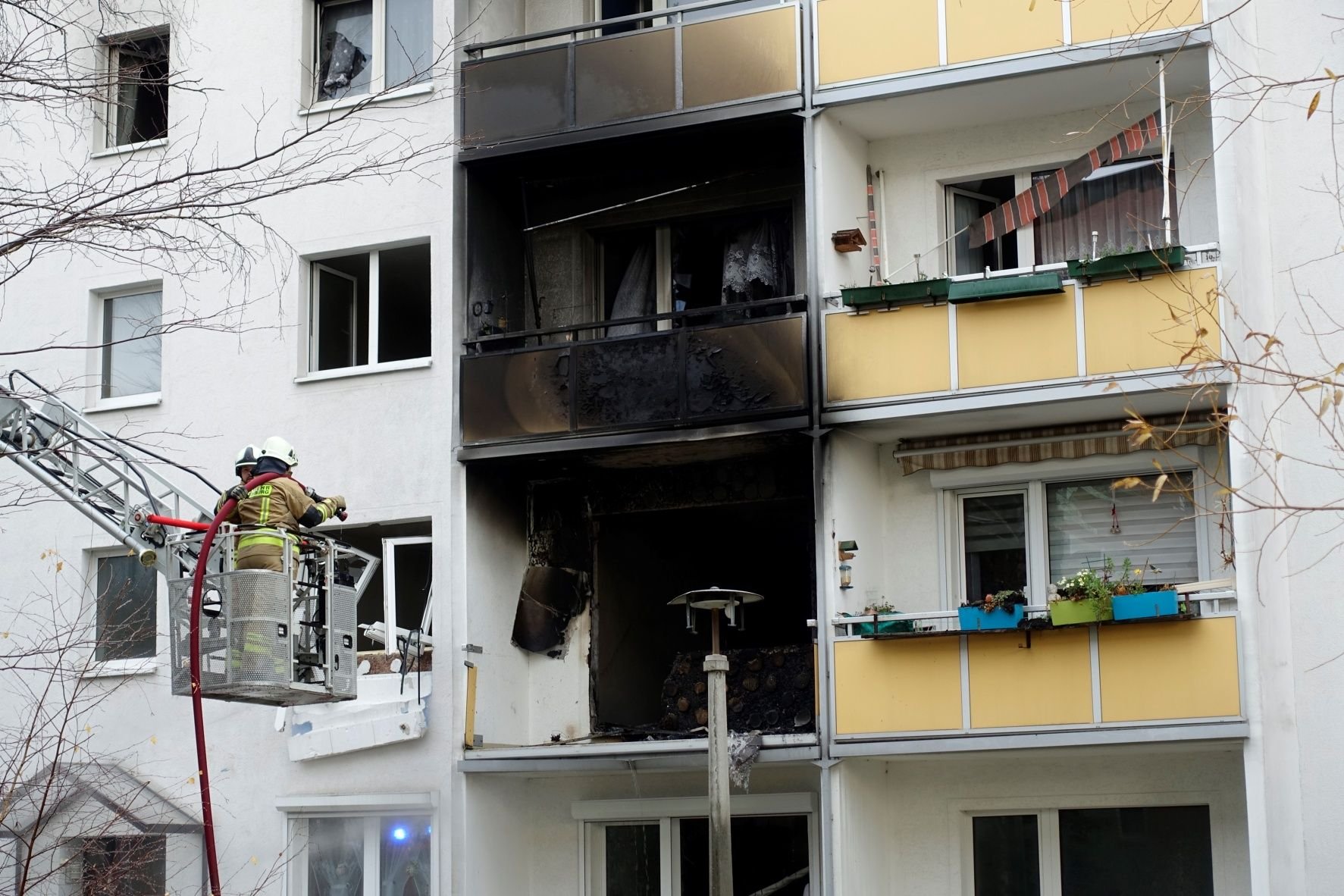 Feuerwehrleute löschen vom Korb einer Drehleiter Glutnester in den durch die Explosion zerstörten Wohnungen in Blankenburg.