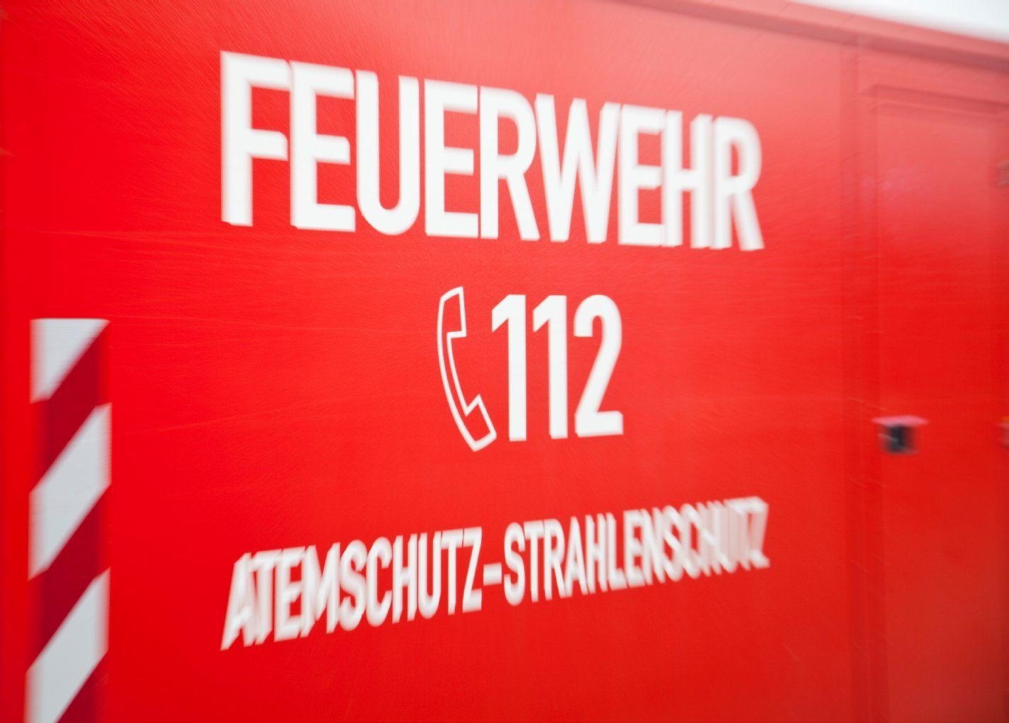 Auf einem Auto der Feuerwehr steht die Notrufnummer geschrieben.