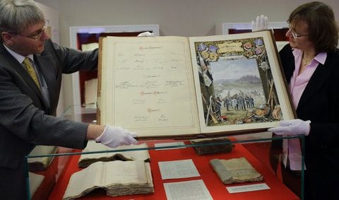 Andreas Erb (li.) und Ulrike Höroldt vom Landeshauptarchiv Sachsen-Anhalt hantieren im Landeshauptarchiv in Magdeburg mit dem Album für General Carl Ludwig Freiherr von Schlotheim aus dem Jahr 1888. (FOTO: DPA)