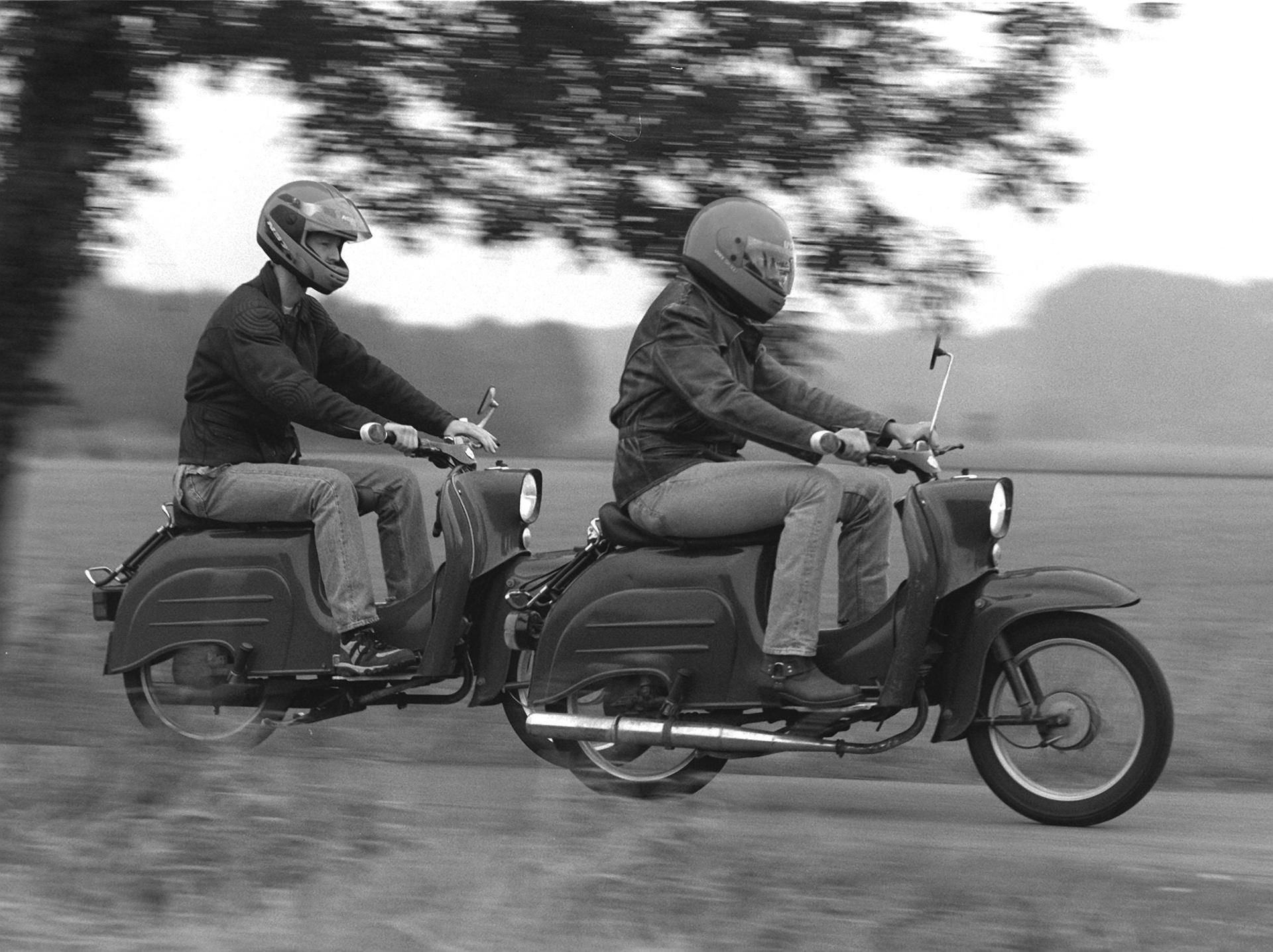 Zwei junge Männer fahren mit ihren "Schwalbe"-Rollern über einen Feldweg. Die Autorin Antje Baumann erklärt in ihrem Werk «Mit der Schwalbe zur Datsche - So sprach der Osten» 50 Begriffe aus der Deutschen Demokratischen Republik.