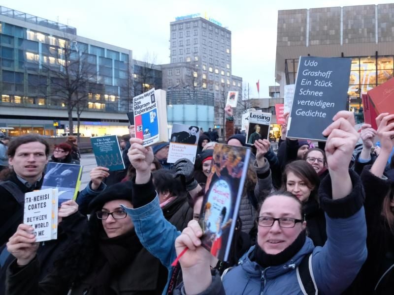 Demonstranten gegen rechte Verlage halten auf dem Augustusplatz in Leipzig Bücher in die Höhe. Foto: Sebastian Willnow