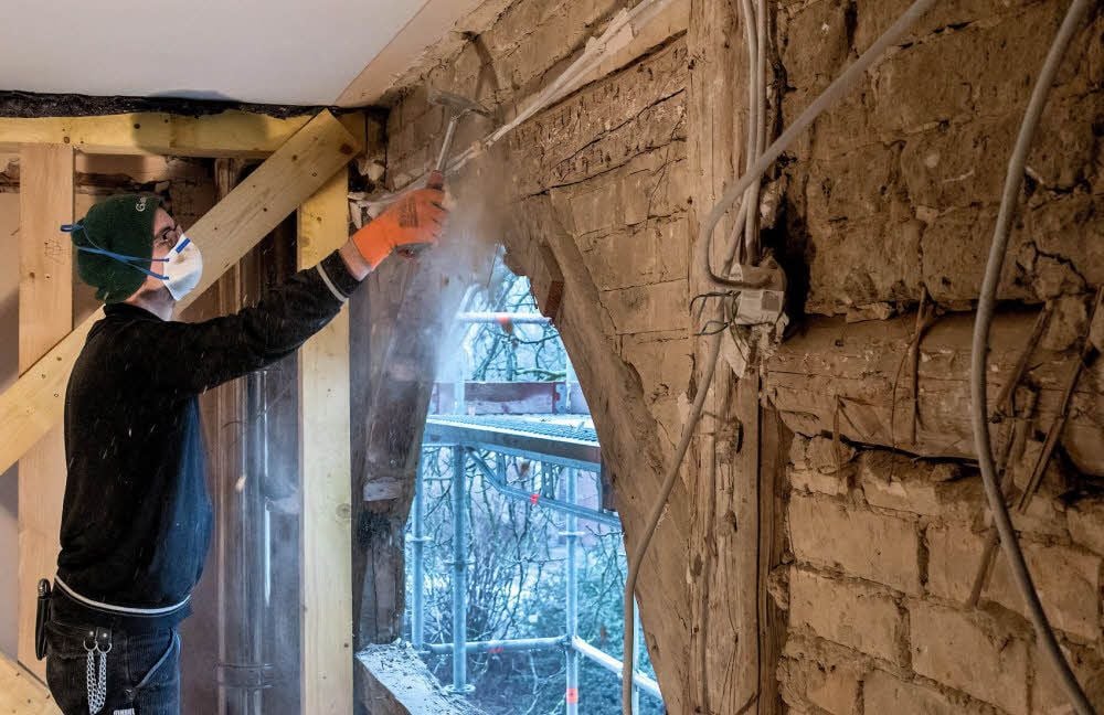 Mit einem Mundschutz gegen den Staub legt Johannes Schmidt das Fachwerk im Bühnenhaus des Goethe-Theaters frei.