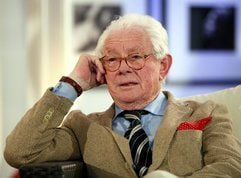 Fotograf David Hamilton sitzt vor der Eröffnung einer Ausstellung in Stuttgart vor seinen Bildern (Foto: dpa)