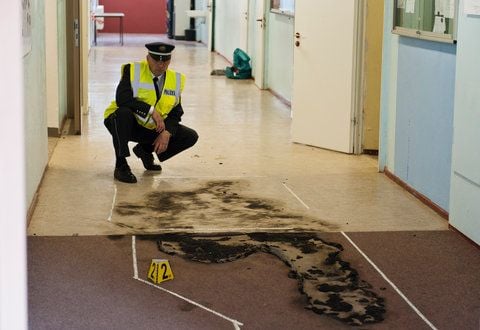 Ein Polizist betrachtet am Mittwoch in einem Flur des Wolterstorff-Gymnasiums in Ballenstedt eine von zwei Brandstellen, an der eine Schülerin am Morgen einen Brandsatz zündete (FOTO: DAPD)