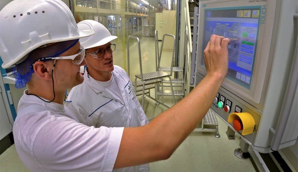 Der ehemalige Azubi Patrick Frutig (vorn) und sein Ausbilder Mario Zörner an der Gießmaschine für Schokotropfen.