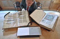 Der Leiter der Sondersammlungen der Leipziger Universitätsbibliothek Albertina, Thomas Fuchs, schaut sich in Leipzig eine Auswahl der historischen Bücher Histroiae (l., 14. Jahrhundert), Biblia germanica (r.,17.02.1483) und ein Stammbucheintrag von Max Klinger (01.03.1872) an. (Foto: dpa)