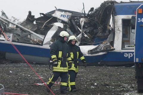 Feuerwehrmänner gehen am Sonntag in Hordorf bei Oschersleben nach dem Zusammenstoss eines privaten Harz-Elbe-Expresses (HEX) mit einem Guterzug vor dem völlig zerstörten Waggon der Regionalbahn. (FOTO: DAPD)