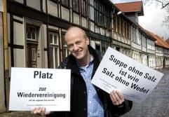 Der Arzt und Dichter Nicolas Nowack steht mit zwei Schildern, auf denen Sprüche zum Nachdenken stehen, in der Innenstadt von Salzwedel.(Foto: dpa)