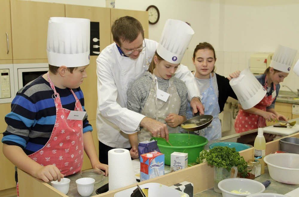 Die Schüler Niklas, Lina und Katharina (von links) kümmern sich mit Mario Kühne um den Crêpes-Teig.