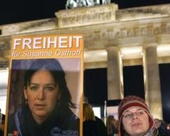Mit einer brennenden Kerze und einem Poster mit der Aufschrift «Freiheit für Susanne Osthoff» stehen Frauen am Mittwoch (13.12.2005) in Berlin vor dem Brandenburger Tor. (Foto: dpa)