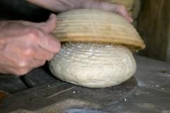 Mit Händen und Hilfe eines Körbchens wird im Rahmen eines historischen Backkurses im Rheinischen Freilichtmuseum Kommern in Mechernich-Kommern (Eifel) ein geschmeidiger Brotteig geknetet. (Foto: dpa)