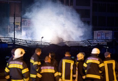 Feuerwehreinsatzkräfte aus Deutschland stehen in der Nacht zu Montag vor einem brennenden Polenmark (Oder-Center-Berlin) nahe der polnischen Ortschaft Cedynia am Grenzübergang nach Hohenwutzen (Brandenburg). (FOTO: DPA)