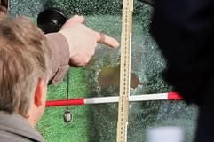 Kriminalpolizisten untersuchen in Berlin am Tatort vor einer Post-Filiale, wo am Morgen bei einem Überfall der Wachmann eines Geldtransporters erschossen wurde, ein Schussloch in der Scheibe eines geparkten Autos. (Foto: dpa)