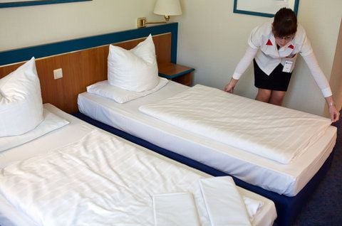 Eine Auszubildende zur Hotelfachfrau macht ein Bett in einem Zimmer im Hotel (FOTO: DPA)